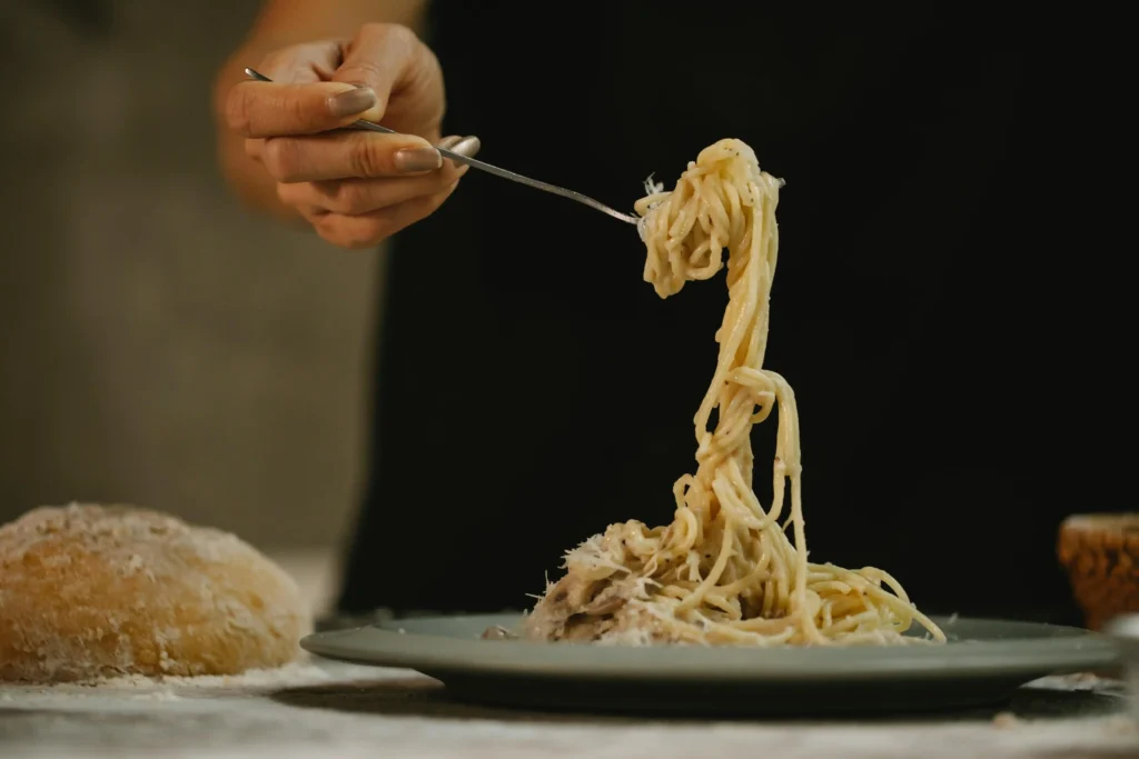 Close-up of spaghetti coated in creamy Cacio e Pepe sauce, with visible black pepper flakes