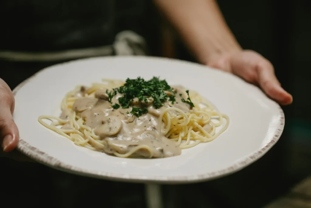 Cacio e Pepe pasta served in a white bowl with a sprinkle of grated Pecorino Romano and black pepper on top