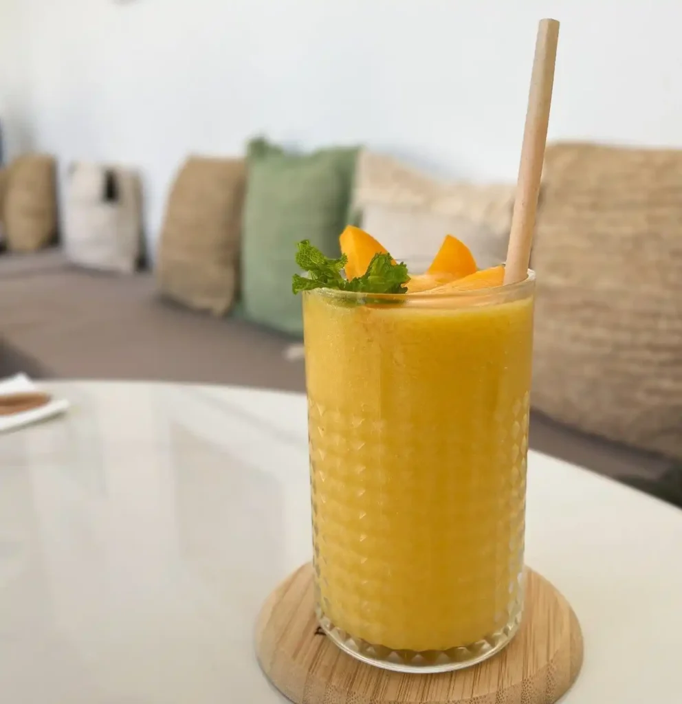 Homemade papaya smoothie served in a glass with a side of fresh fruits