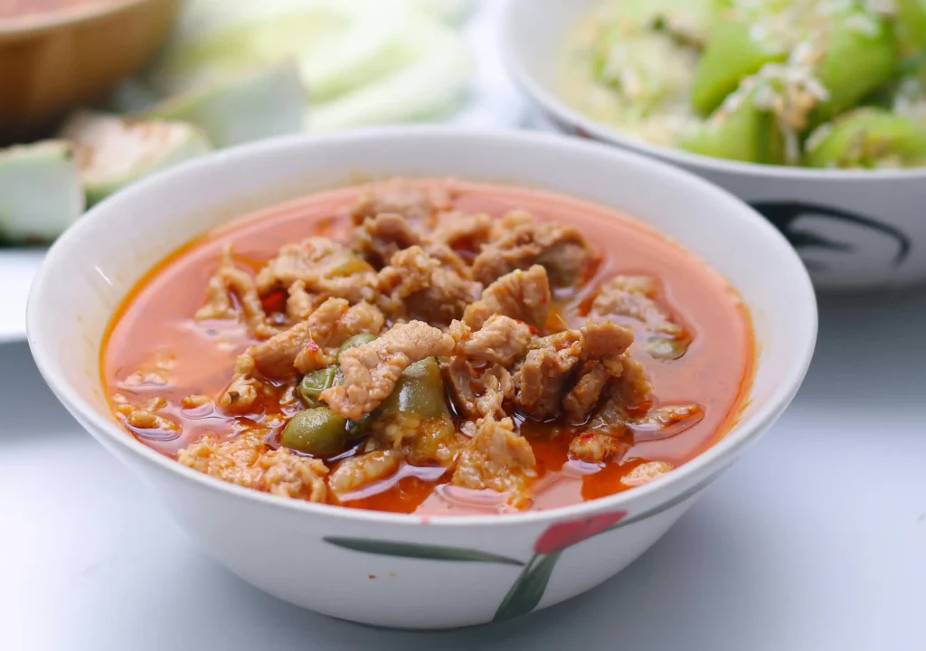 Ladle of homemade Colorado Green Chili Recipe being served from a pot