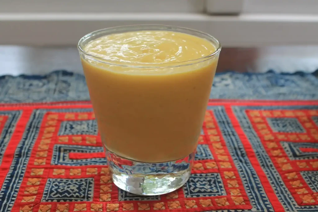 Freshly blended papaya smoothie recipe in a glass garnished with papaya slices