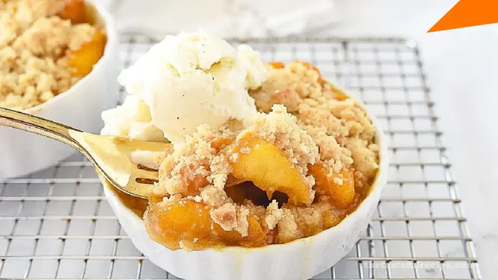 A beautifully plated peach cobbler dessert on a wooden table with a scoop of ice cream