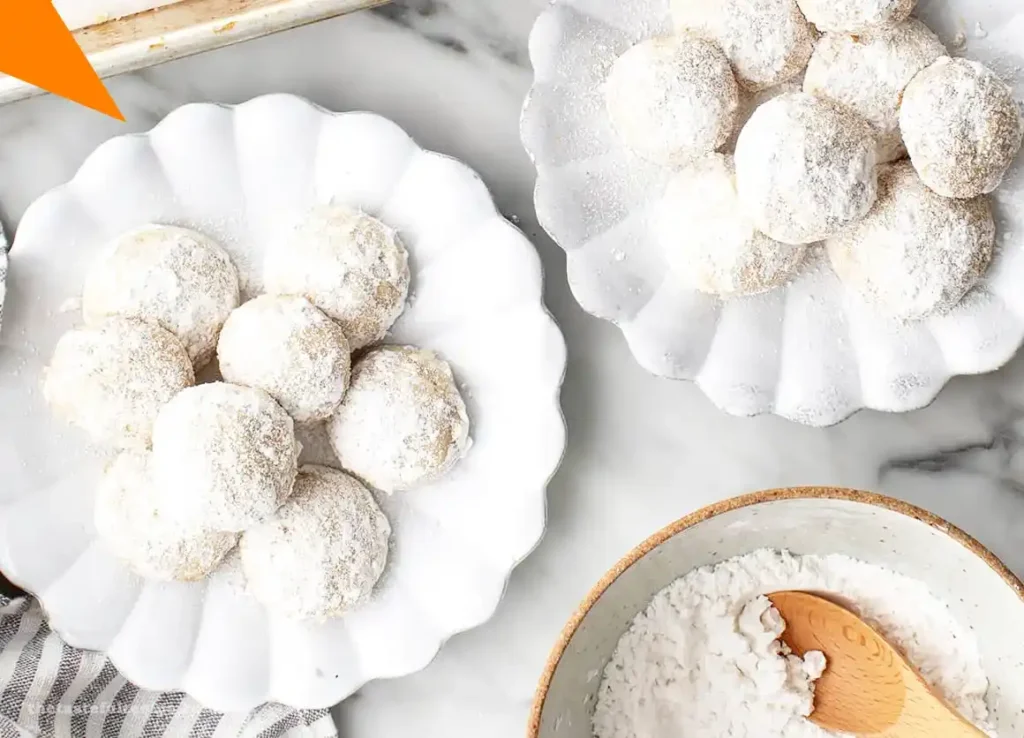 Close-up of Mexican Wedding Cookies dusted with powdered sugar on a white plate