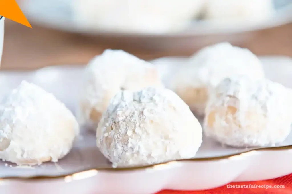 Freshly baked Mexican Wedding Cookies with pecans arranged on a baking sheet